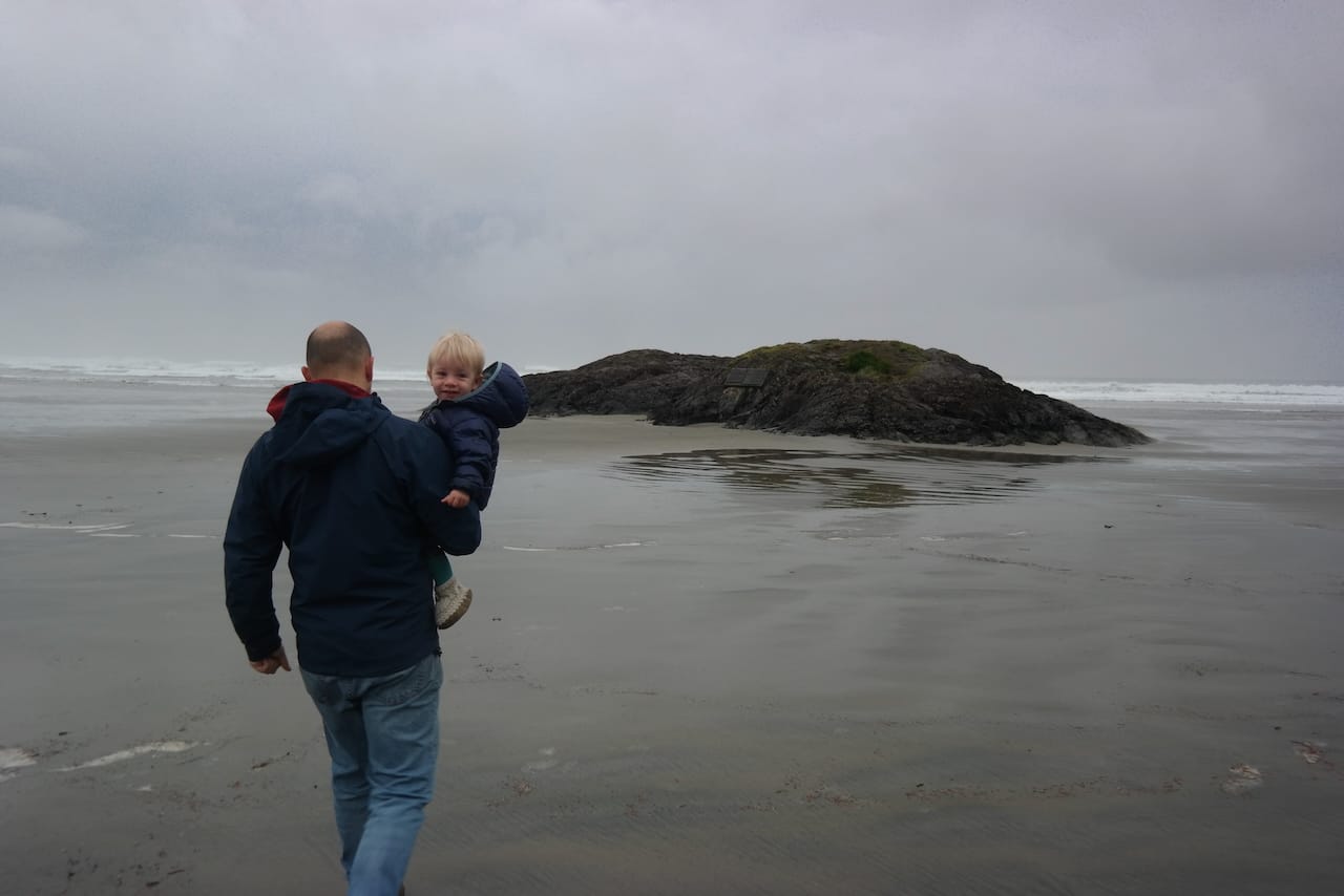Steve Adams carrying his son to a rock in Tofino, BC